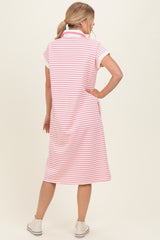 woman wearing a pink and white striped short sleeve polo dress, standing with her back to the camera