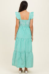 woman wearing a green and white striped maxi dress with ruffled sleeves and a tiered skirt, shown from the back
