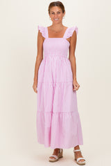 woman wearing a pink and white striped maxi dress with ruffle sleeves and a tiered skirt