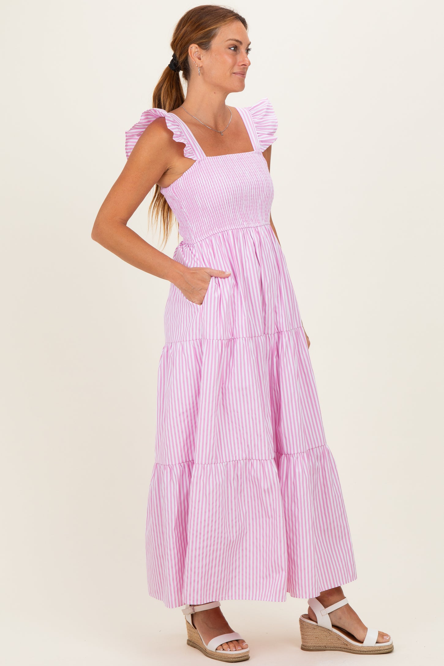 woman wearing a pink and white striped maxi dress with ruffle straps and pockets