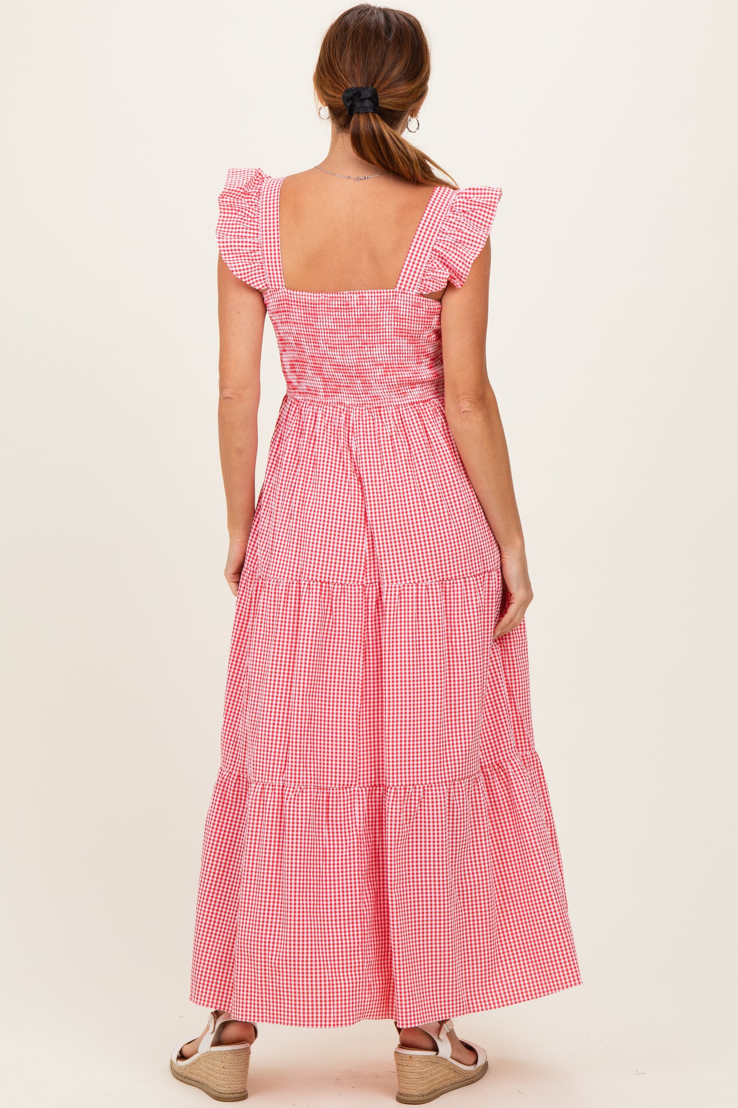 woman wearing a red and white gingham maxi dress with flutter sleeves and a tiered skirt from the back