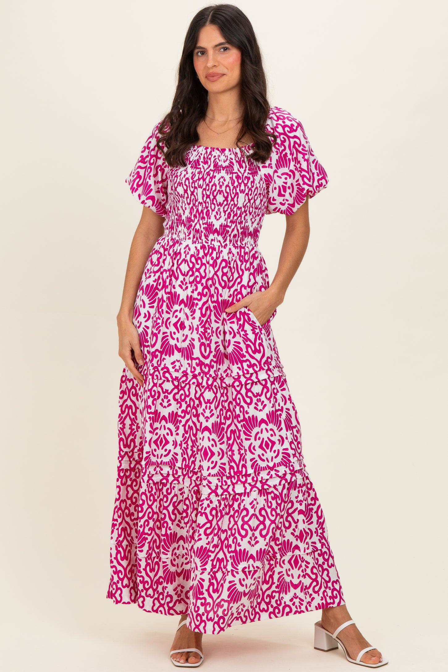woman wearing a pink floral maxi dress with short flutter sleeves and pockets