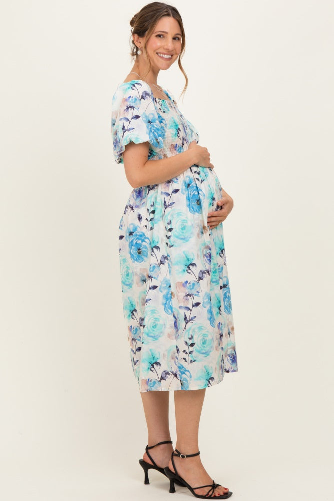 woman wearing a floral print maternity dress in blue and white, showcasing her baby bump with a side view