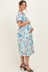 woman wearing a floral print maternity dress in blue and white, showcasing her baby bump with a side view