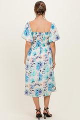 woman wearing a floral maternity dress with puff sleeves and a smocked back, showing a baby bump from the side