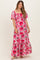 woman wearing a pink floral maternity maxi dress with puff sleeves and a tiered skirt, showcasing her baby bump