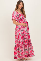 woman wearing a pink and floral maternity maxi dress and holding her baby bump