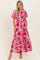 woman wearing a floral pink maxi dress with puff sleeves and pockets, standing and smiling