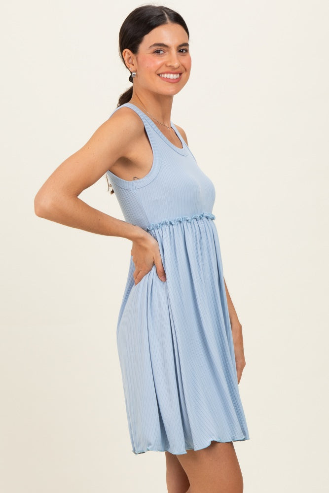 woman wearing a light blue sleeveless dress with a cinched waist and pockets, smiling and standing sideways