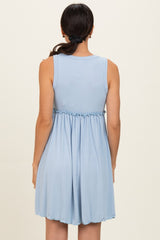 woman wearing a light blue sleeveless tiered dress with a gathered waist and back pleats