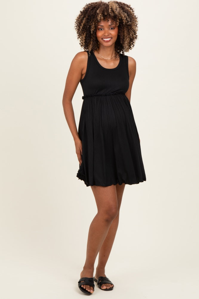 woman wearing a black maternity dress with a fitted bodice and flowing skirt, showing her baby bump