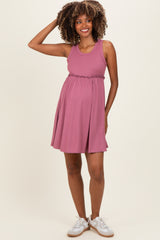 woman wearing a mauve sleeveless maternity dress with a stretchy waistband and a visible baby bump
