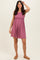 woman wearing a sleeveless pink ribbed sundress with a gathered waist and smiling at the camera