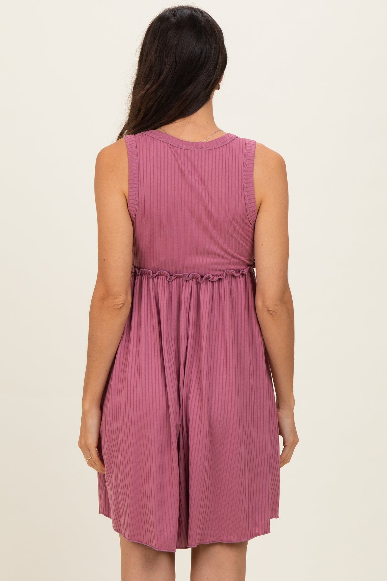 woman wearing a mauve sleeveless ribbed dress with an elastic waistband and a relaxed fit