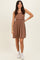 woman wearing a sleeveless brown ribbed dress with a flared skirt and white sneakers