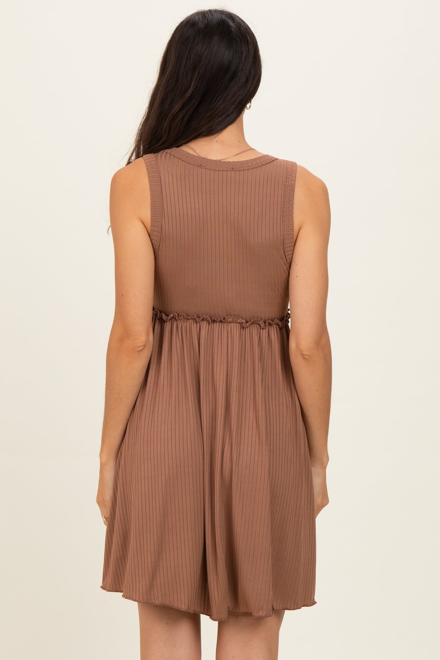 woman wearing a brown sleeveless ribbed dress with a cinched waist and flowing skirt, back view