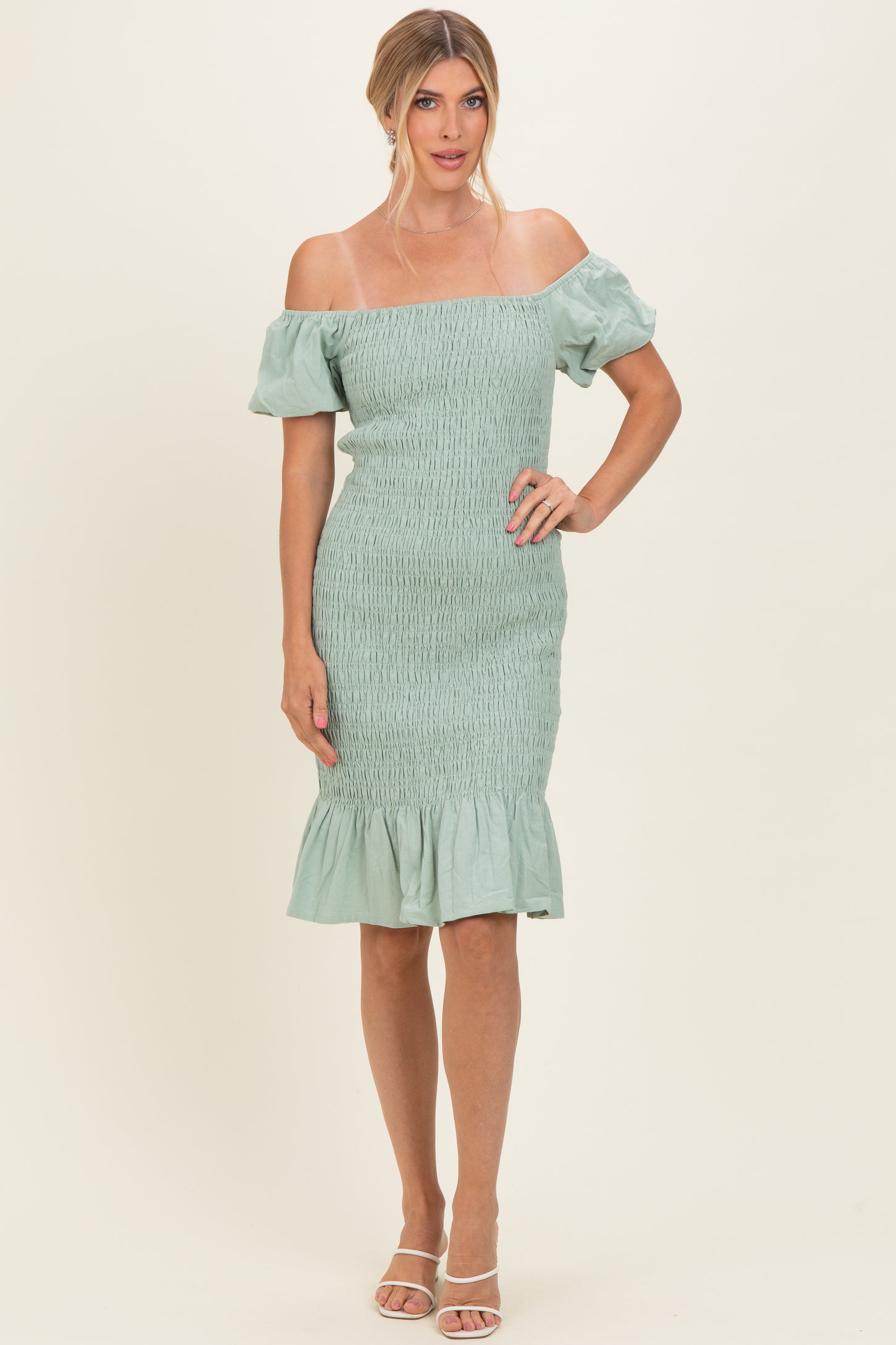 woman wearing a mint green off-the-shoulder fitted dress with puff sleeves and a ruffled hemline