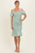 woman wearing a mint green off-the-shoulder fitted dress with puff sleeves and a ruffled hemline