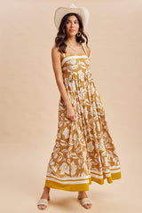 woman wearing a mustard yellow floral maxi dress with a fitted bodice and flowing skirt, accessorized with a straw hat