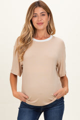 woman wearing a beige maternity top with a white neckline and holding her baby bump