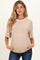 woman wearing a beige maternity top with a white neckline and holding her baby bump