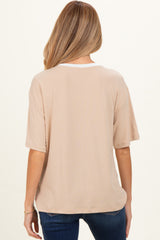 woman wearing a beige oversized maternity t-shirt, styled with a contrasting white neckline, seen from the back