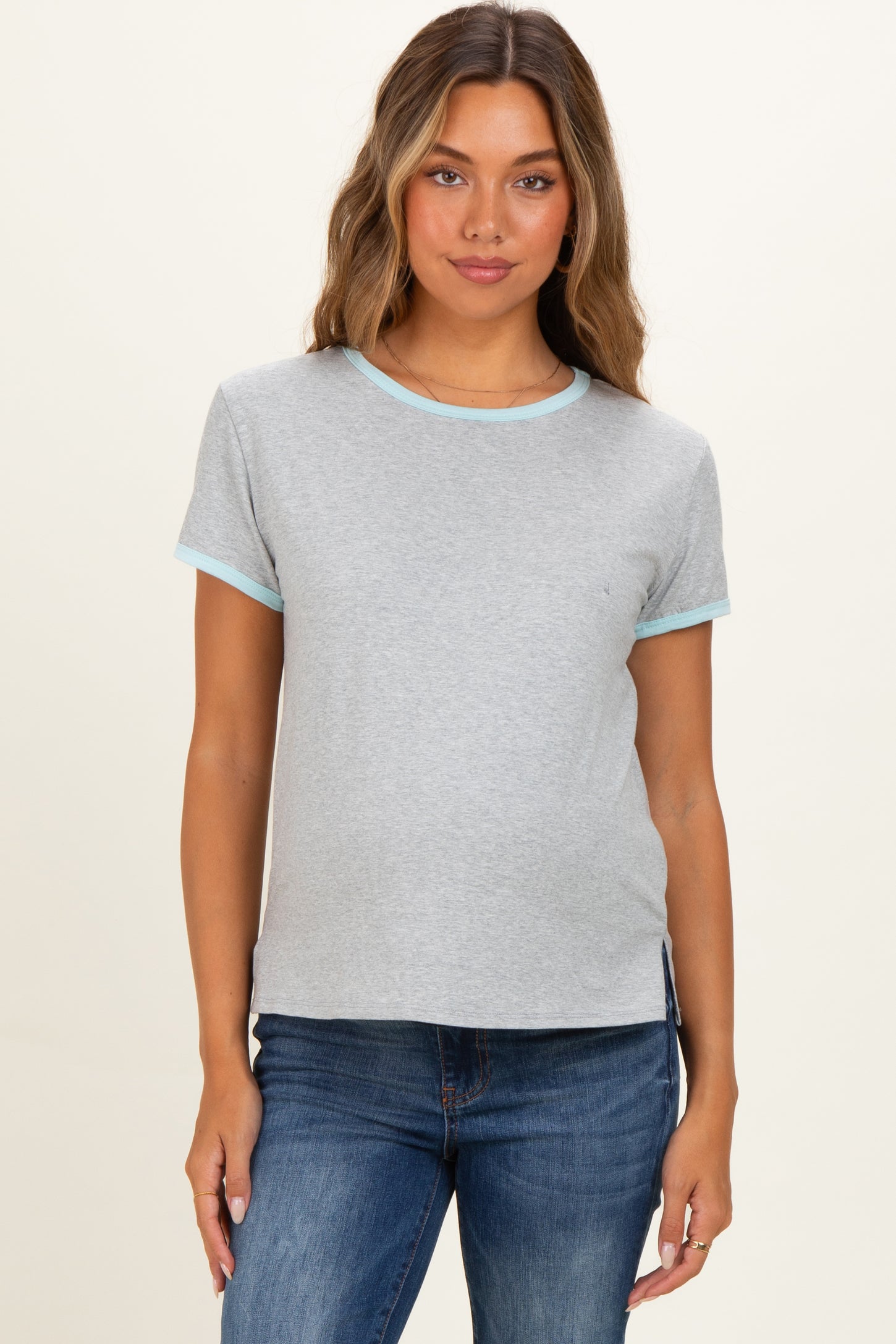 woman wearing a light gray maternity t-shirt with teal trim and side slits, showing a small baby bump