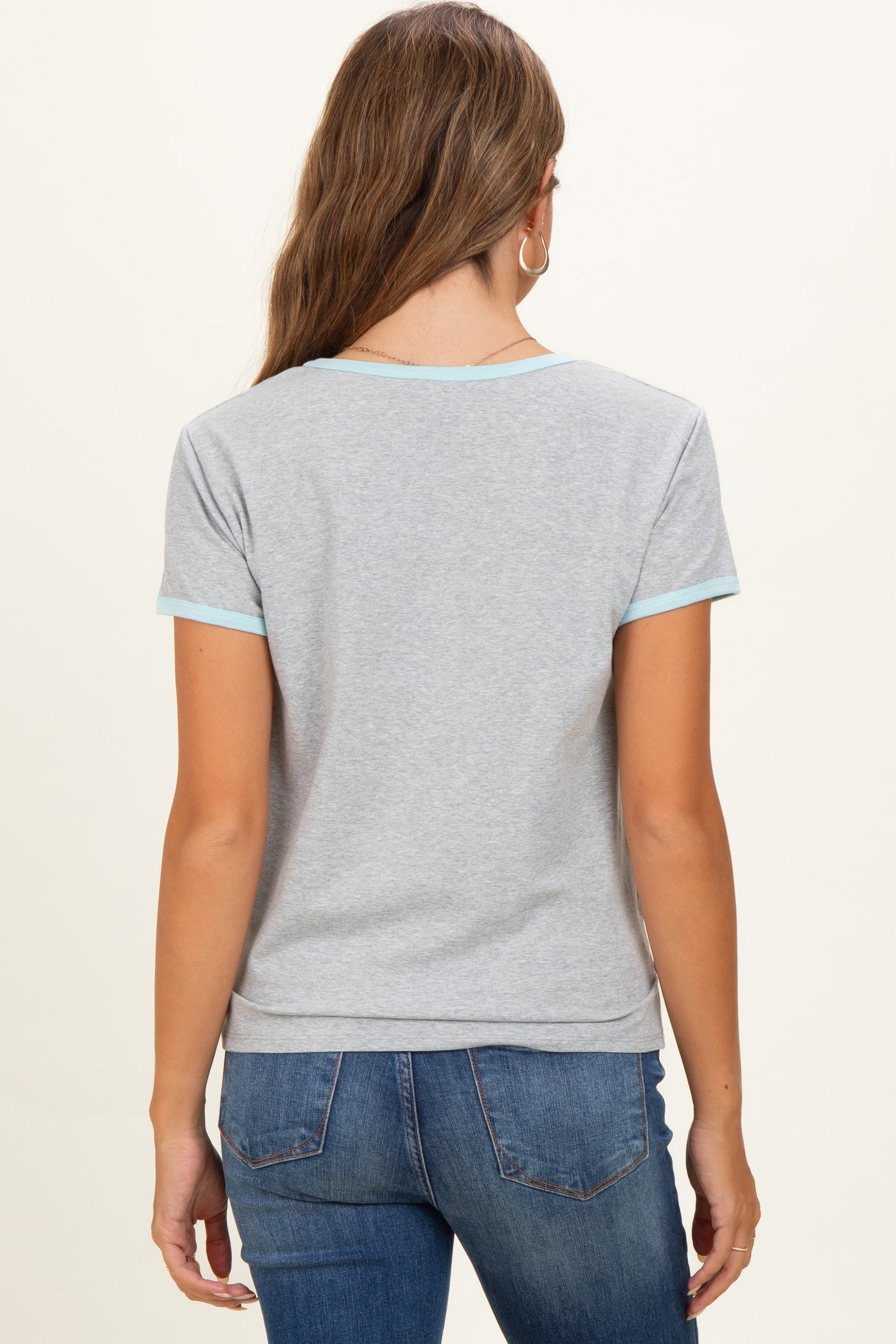 woman wearing a gray maternity t-shirt with light blue trim, view of the back and styled with jeans
