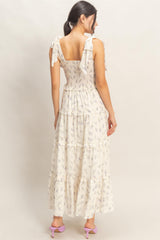 woman wearing a floral print maxi dress with tied shoulder straps and a tiered skirt, shown from the back