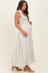 woman wearing a floral tiered maternity maxi dress and cradling her baby bump