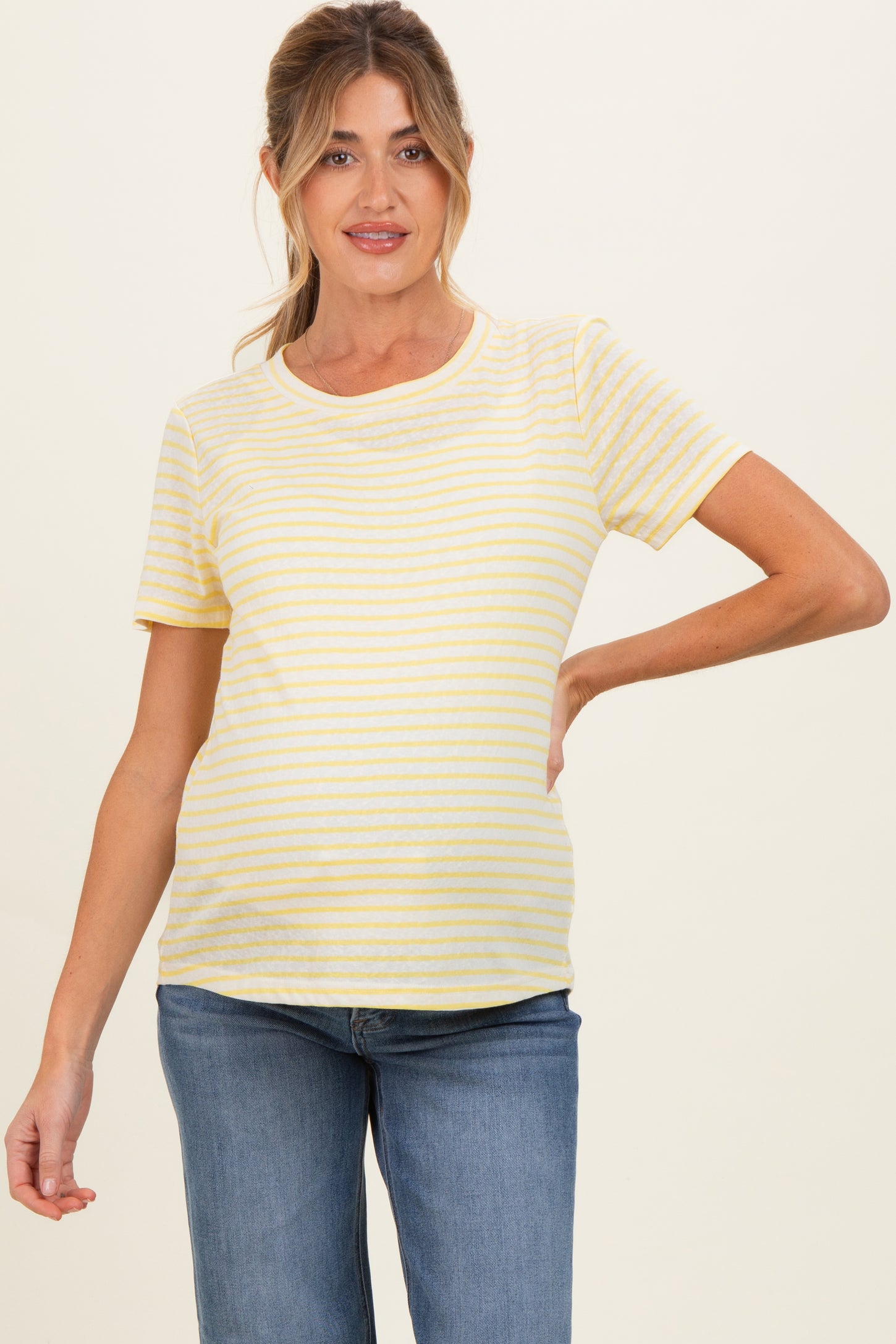 woman wearing a yellow and white striped maternity t-shirt with a visible baby bump and paired with blue jeans