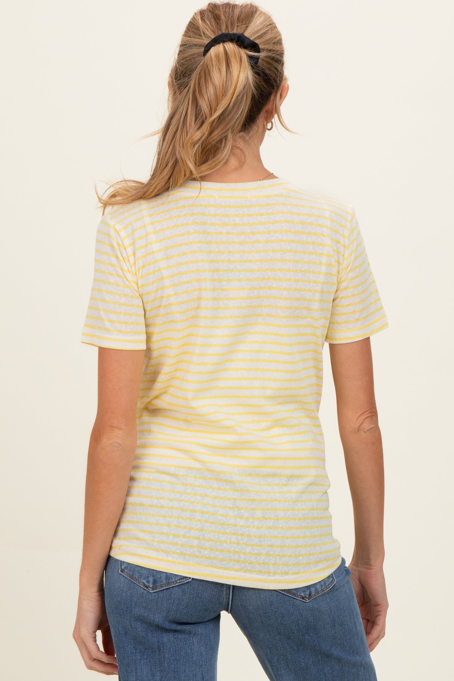 woman wearing a yellow and white striped maternity t-shirt from the back with blue jeans