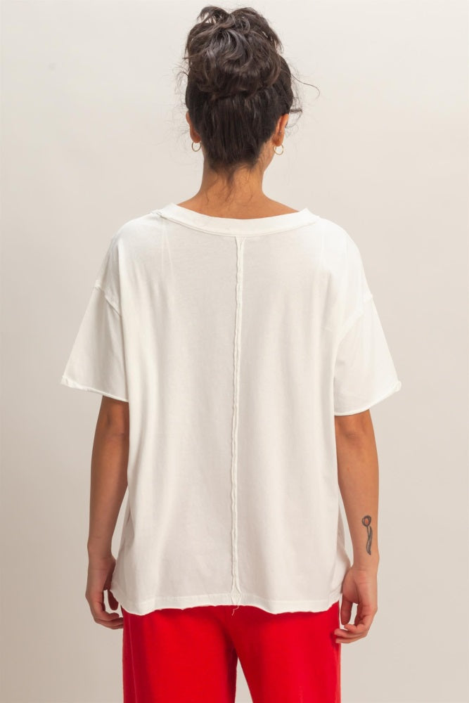 woman wearing a white oversized t-shirt with a back seam detail and red pants