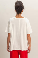 woman wearing a white oversized t-shirt with a back seam detail and red pants