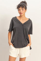 woman wearing a dark gray oversized v-neck t-shirt with short sleeves and relaxed fit, paired with cream shorts