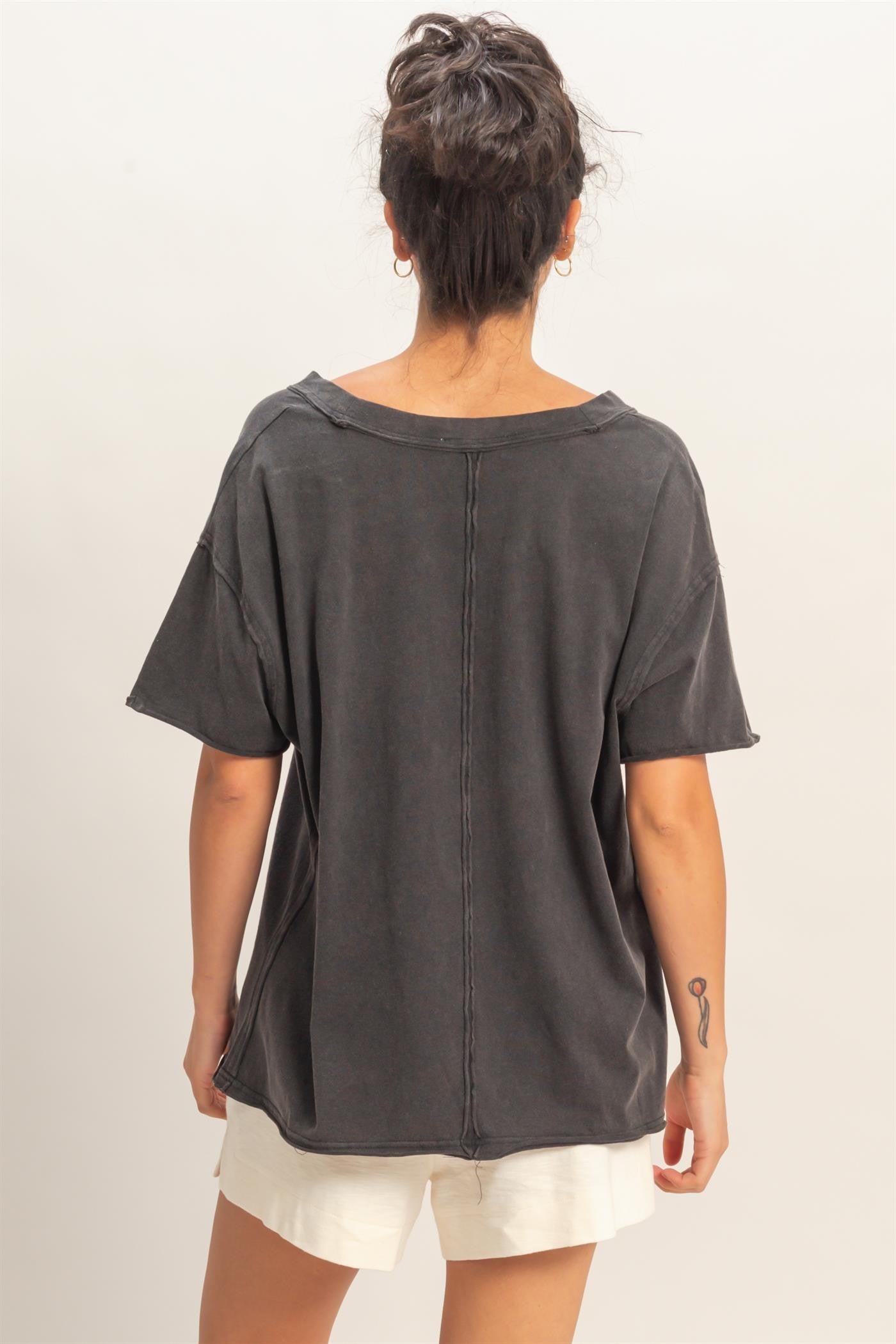 woman wearing a dark gray oversized short sleeve top with a relaxed fit and raw hem, viewed from the back