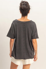 woman wearing a dark gray oversized short sleeve top with a relaxed fit and raw hem, viewed from the back