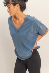 woman wearing a faded blue v-neck oversized t-shirt with rolled sleeves and black leggings