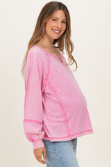 woman wearing a pink long sleeve maternity top with contrasting stitching and a visible baby bump