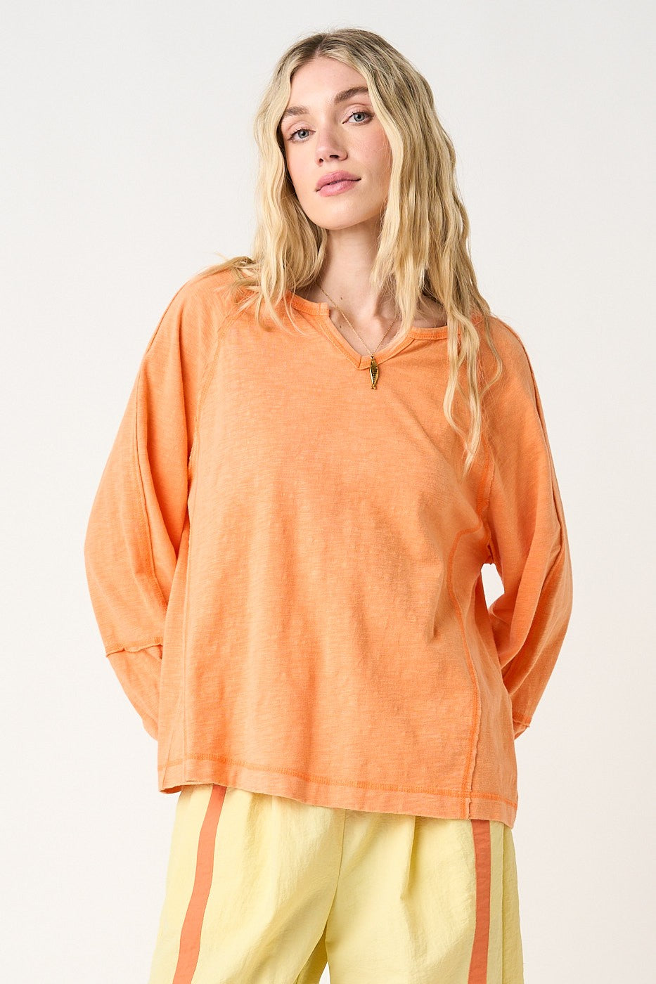 woman wearing an oversized orange long sleeve top with a relaxed fit and light yellow pants
