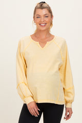 woman wearing a light yellow long sleeve maternity top with a v-neck and balloon sleeves, showing her baby bump