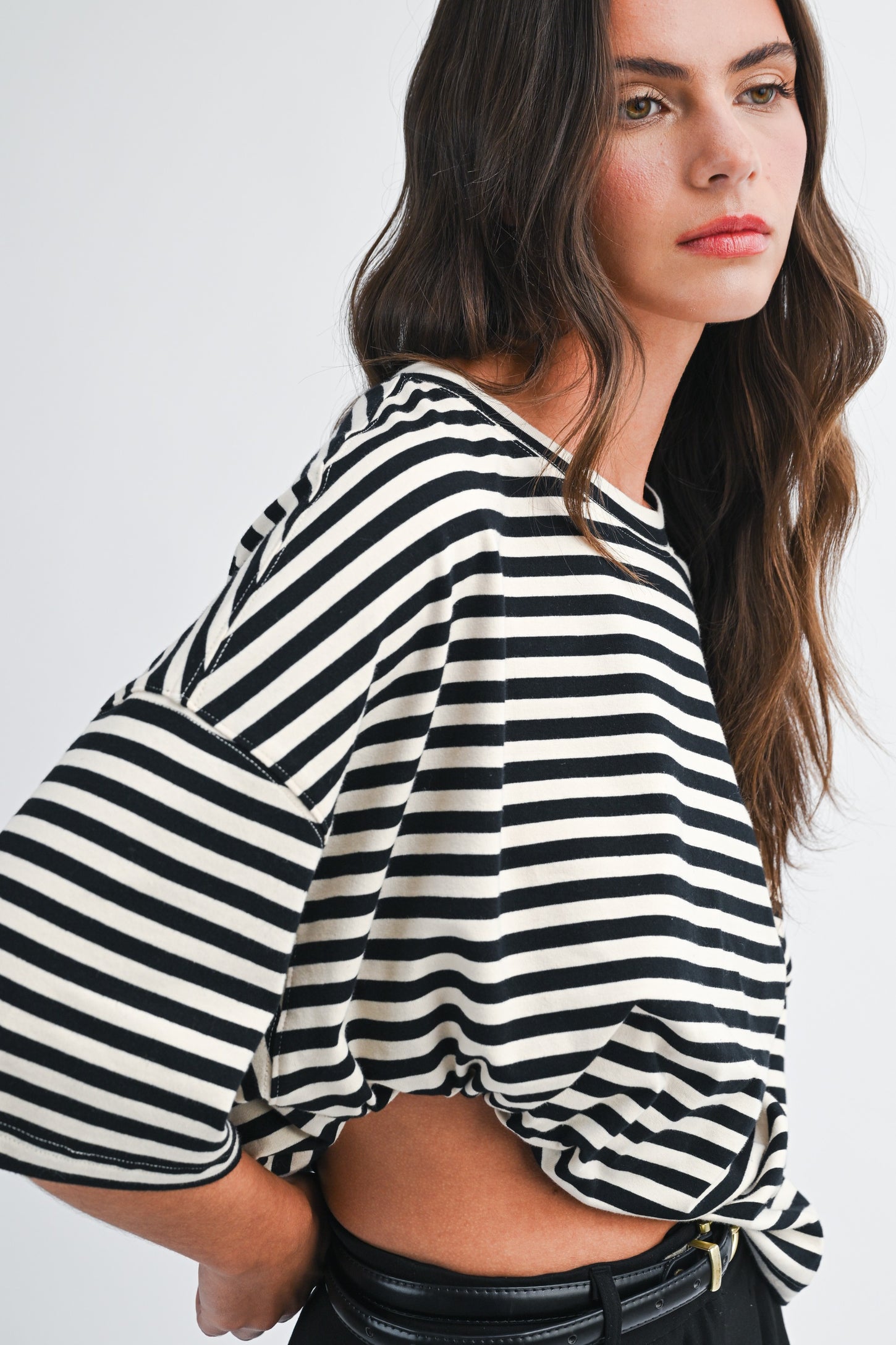woman wearing a black and white striped oversized tee with short sleeves and a knotted front detail