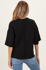 woman wearing a black oversized maternity sweatshirt with a back seam detail, paired with light blue jeans