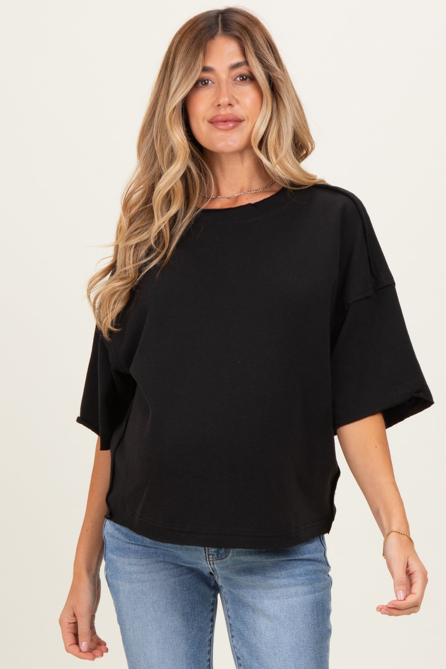 woman wearing a black oversized maternity sweatshirt with short sleeves and a relaxed fit, showing her baby bump