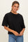 woman wearing a black oversized short sleeve top with a relaxed fit and denim jeans