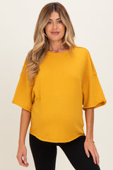 woman wearing a mustard yellow maternity top with a relaxed fit and short sleeves