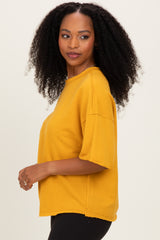 woman wearing a mustard yellow oversized t-shirt with short sleeves and raw hem details