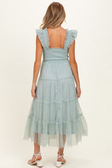 woman wearing a light blue maternity dress with ruffled sleeves and a tiered tulle skirt, showcasing her baby bump