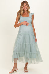 woman wearing a mint green maternity dress with ruffle straps and tiered tulle skirt, showcasing her baby bump