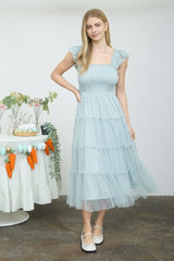 woman wearing a light blue tiered midi dress with ruffle sleeves and a smocked bodice